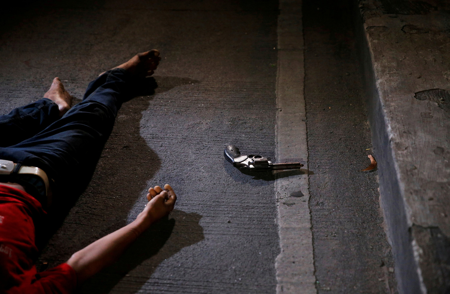 A revolver is seen near the body of a man killed by police after drugs were found in his pockets in Manila, Philippines, Aug. 17, 2017. Catholic bishops in the Philippines broke what they described as their “collective silence” over “many disturbing issues” that have confronted the country in recent months.